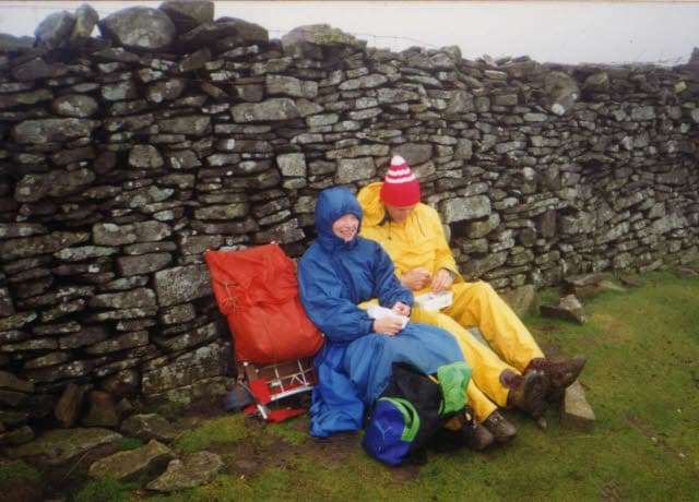 A couple in waterproofs sitting at a dry stone wall on August 1994 on a holiday near Gordale Scar in Yorkshire.