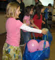Children carrying balloons in large bags.