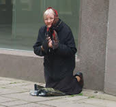 A poor woman kneeling, begging for money in an impossible situation. Feeling desperate and empty?