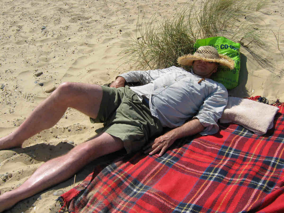 Stress free lying on a beach relaxing and snoozing.