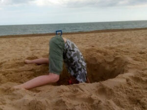 A lad putting his head into a large hole on the beach. Articles on church stuff, Communion, baptism, leadership problems,  Holy Spirit filling, Toronto Blessing, Bible Truths revealed and personal faith.